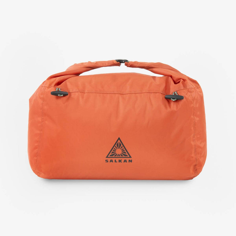 Salkan Laundry Bag in burnt orange, closed roll-top view with carry handle and clip closures