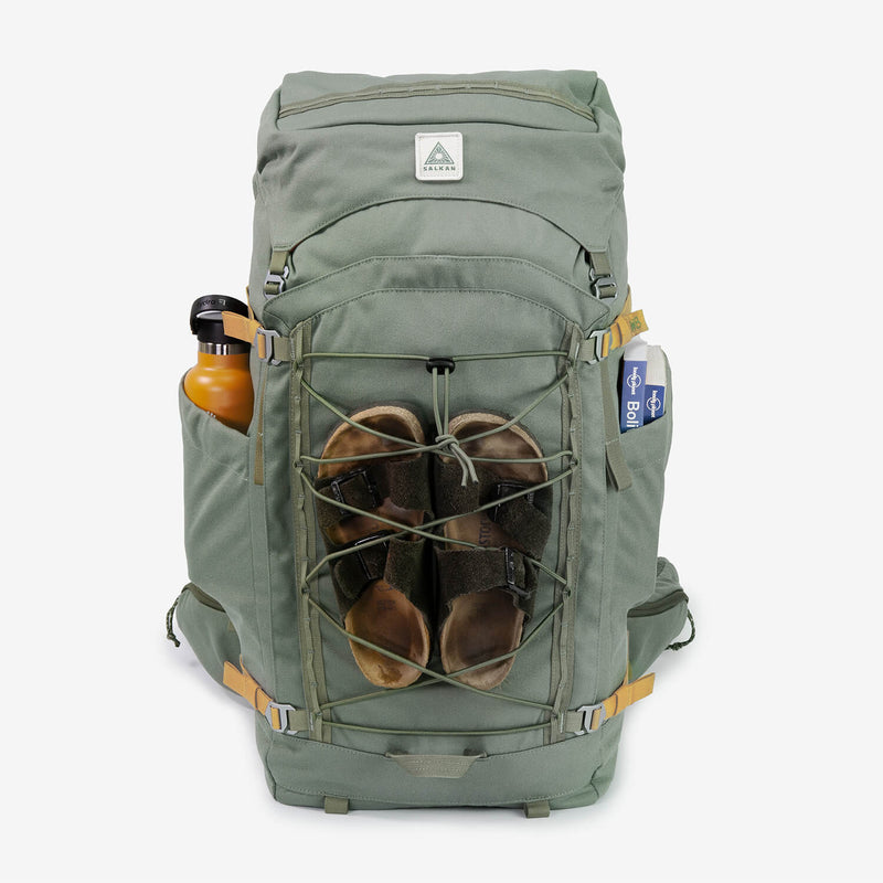 Salkan Longhaul 45L in sage green, front view packed with sandals bungeed on and water bottle in side pocket